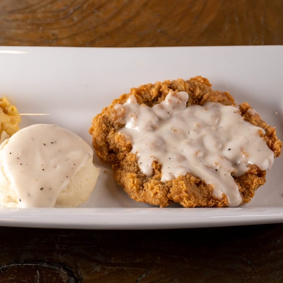 Crispy fried chicken steak smothered in white gravy, served with mashed potatoes and macaroni and cheese.