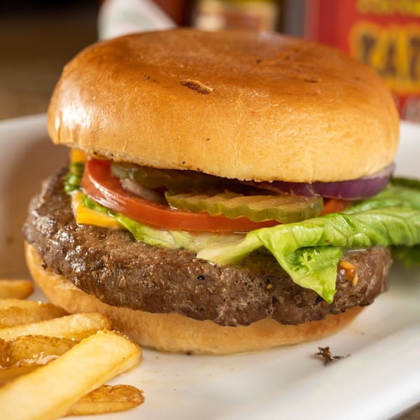 A juicy burger with lettuce, tomato, onion, pickles, and cheese, served with fries.