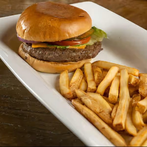 Cheeseburger with lettuce, tomato, onion, and pickles, served with a side of french fries.