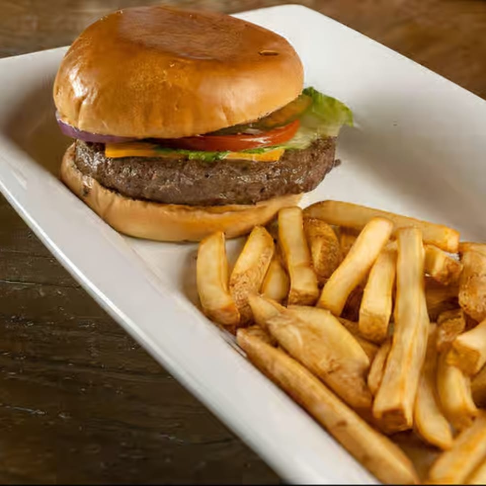 Cheeseburger with lettuce, tomato, onion, and pickles, served with a side of french fries.